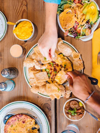 Top-down view of a table filled with food with two hands reaching for items on the table.