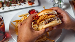 hands holding burger from Rouj Creole