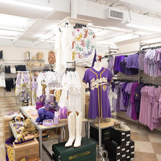 Bella Bella in Baton Rouge displaying purple LSU apparel, dresses, t-shirts, and accessories on racks and mannequins.
